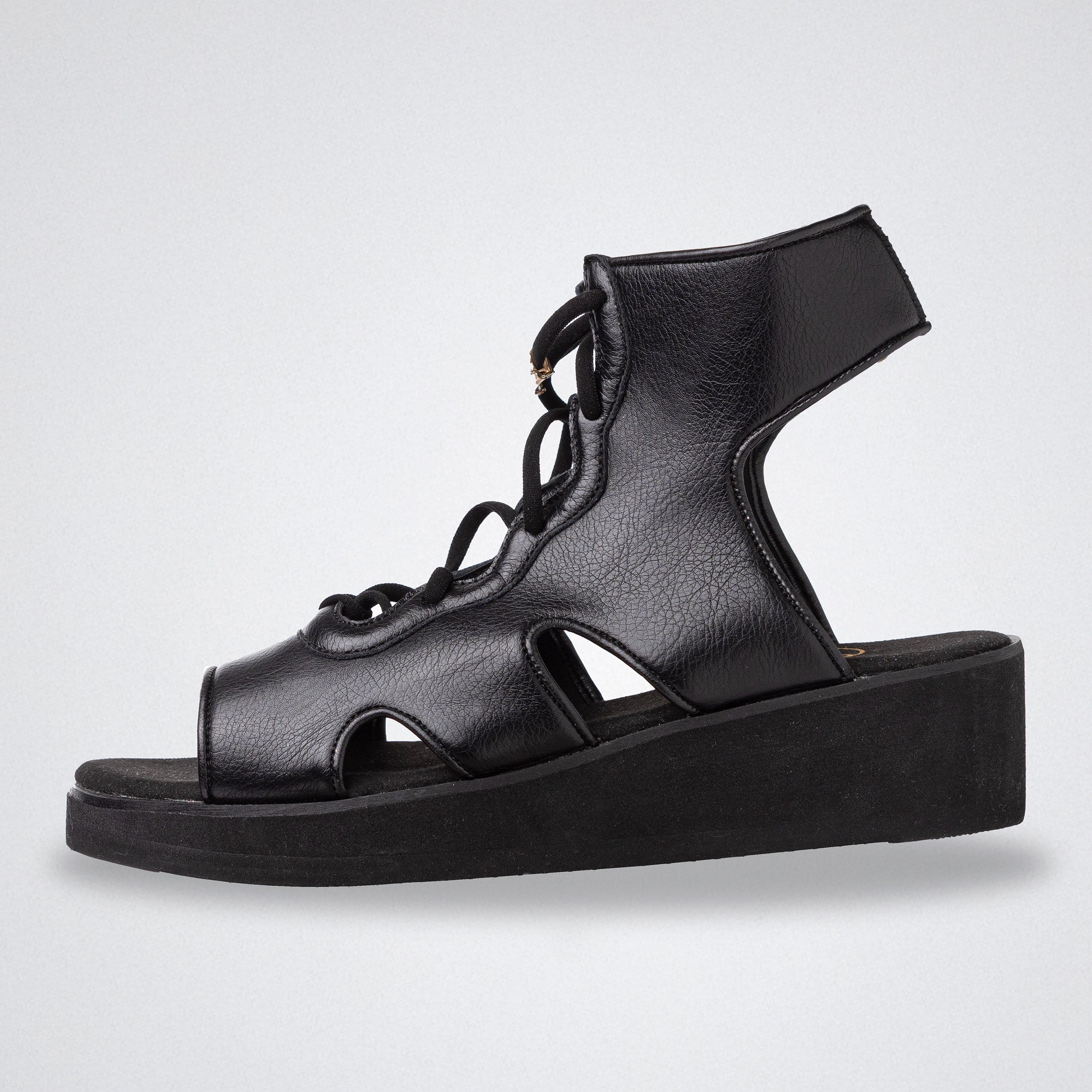 Black sandal with cut-out design on a light gray background